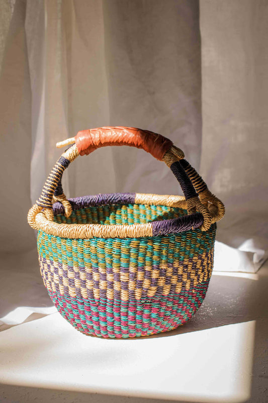 Woven basket with multicolored handle on a light surface