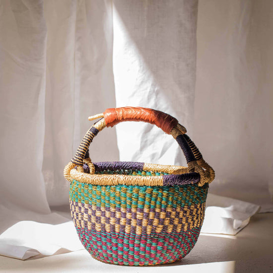 Multicolored woven basket with a handle on a light background