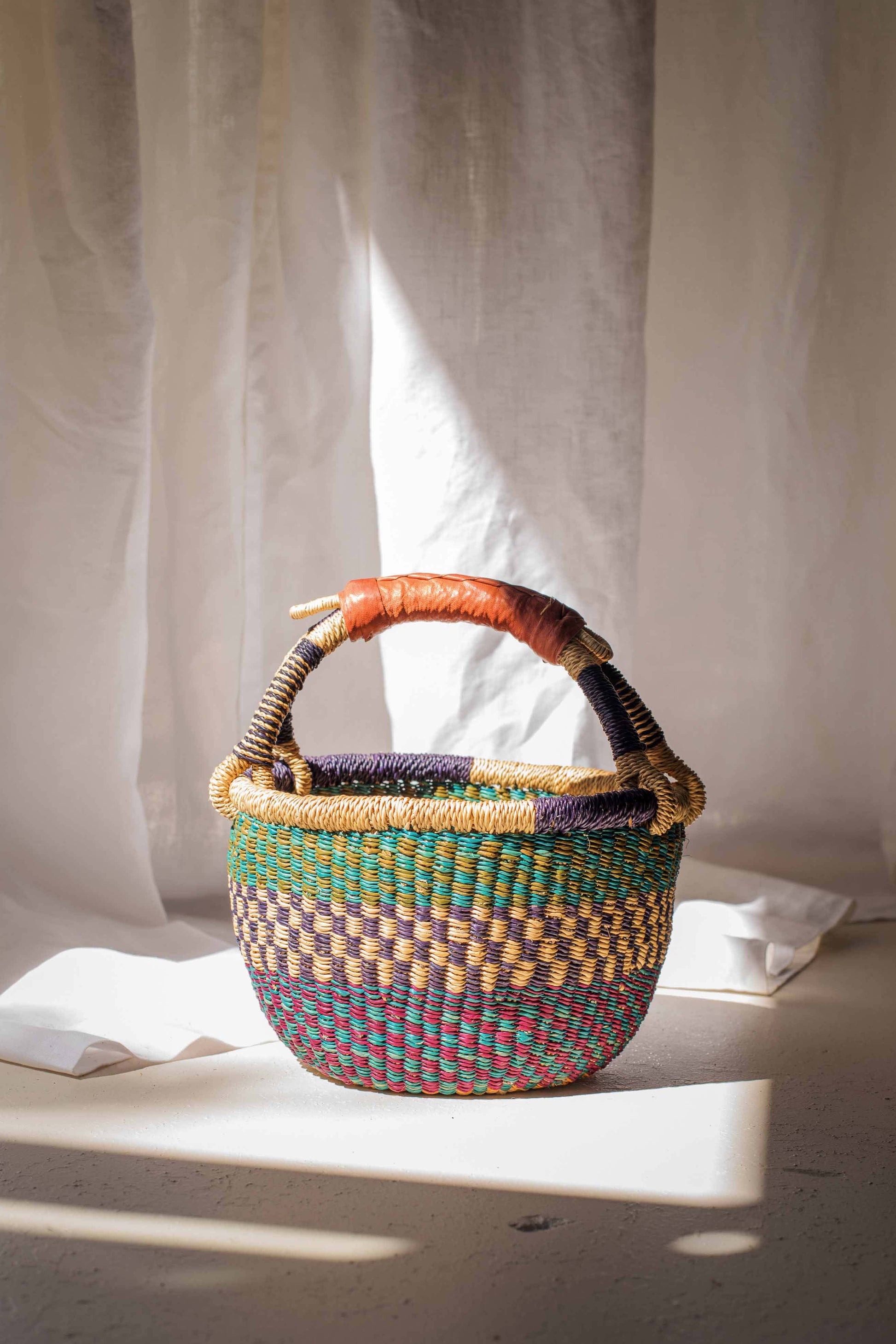Multicolored woven basket with a handle on a light background