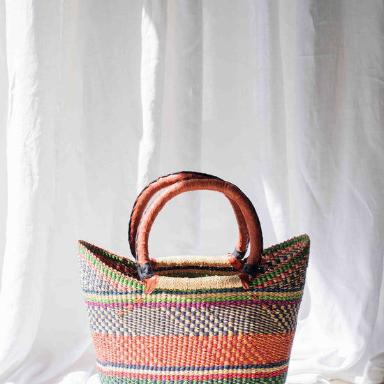 Colorful woven basket with wooden handles on a white background