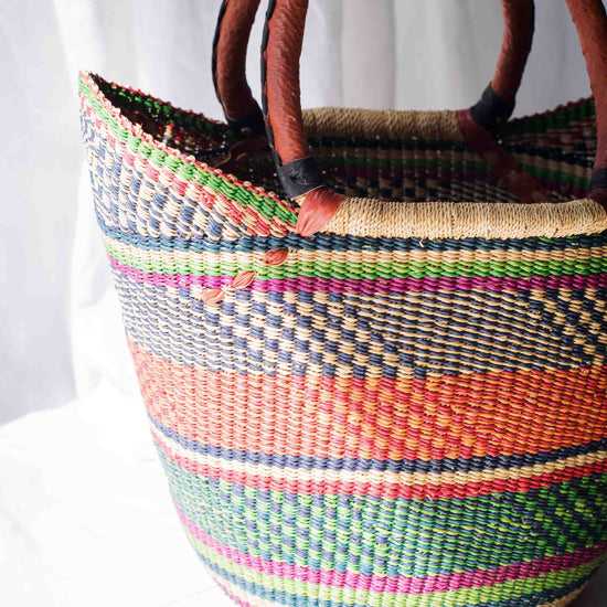 Woven basket with colorful stripes and wooden handles on a white background