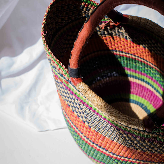 Colorful woven basket with a patterned handle on a white background