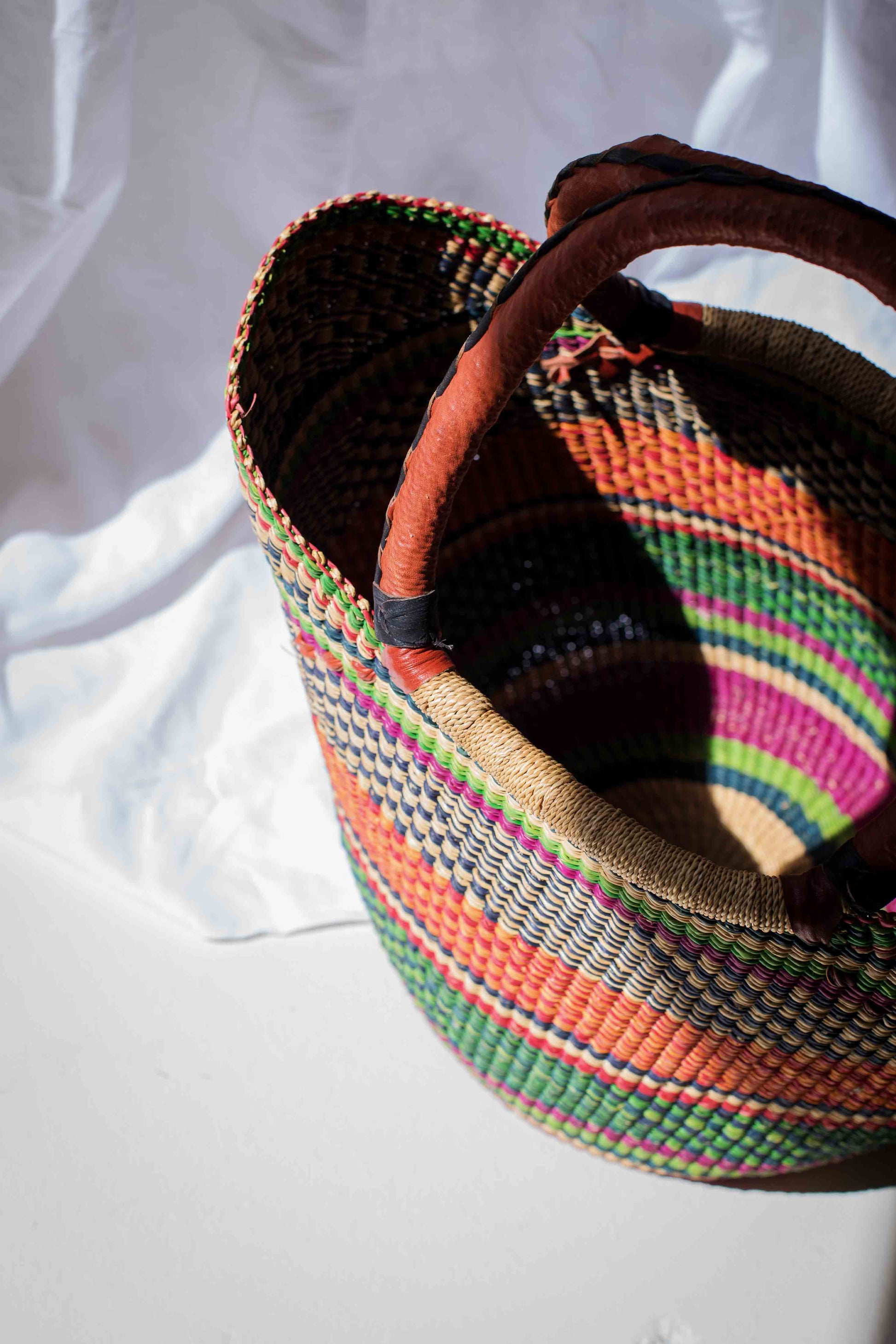 Colorful woven basket with a patterned handle on a white background