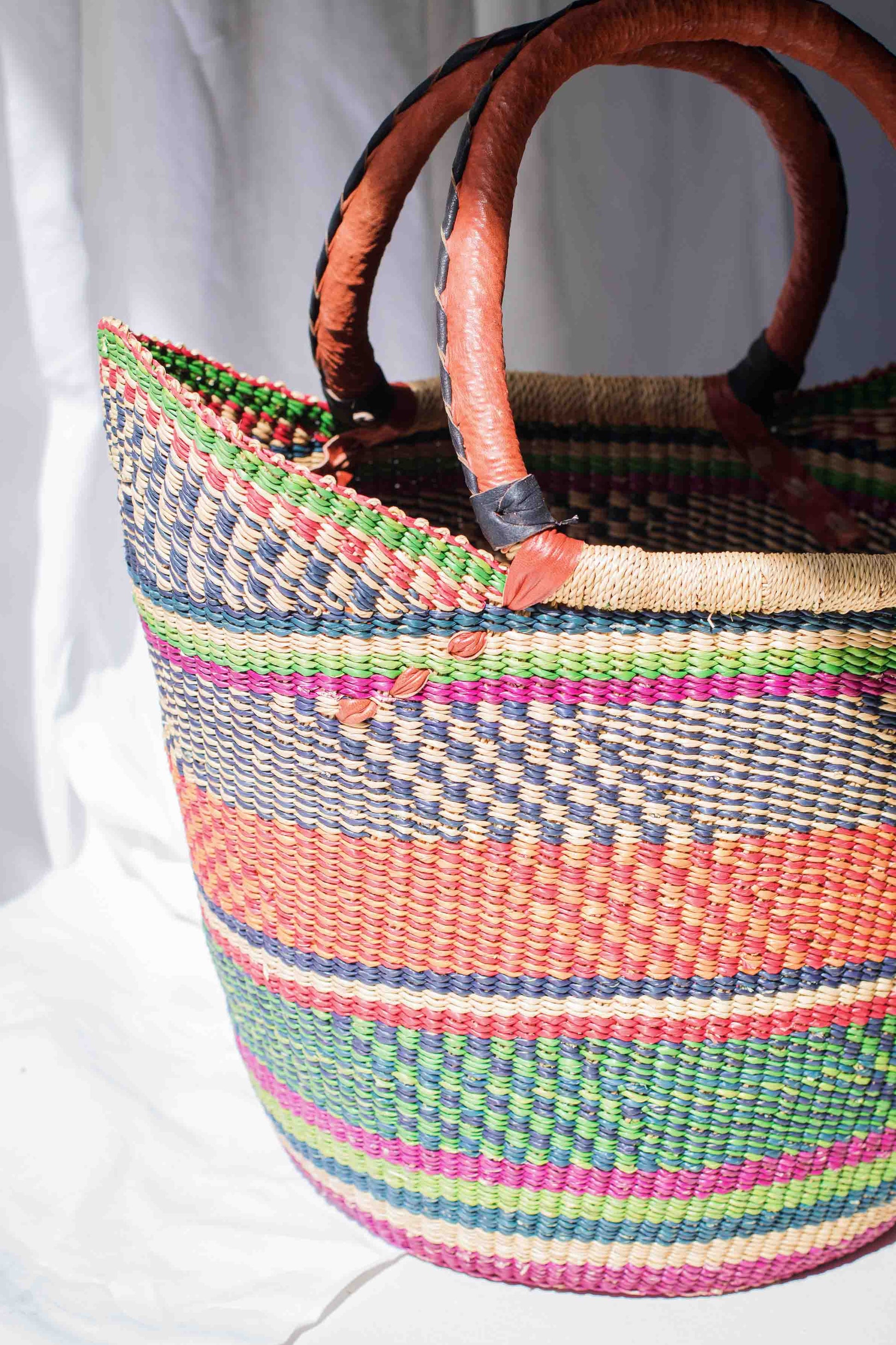 Colorful woven basket with wooden handles on a white background