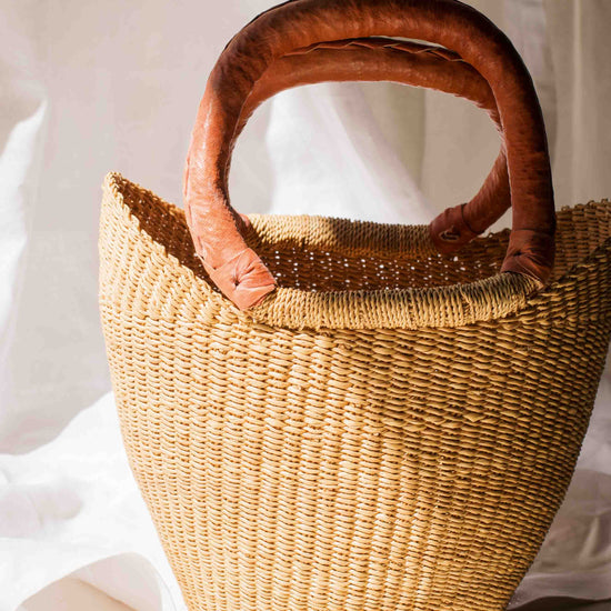 Woven basket with wooden handle on a white background