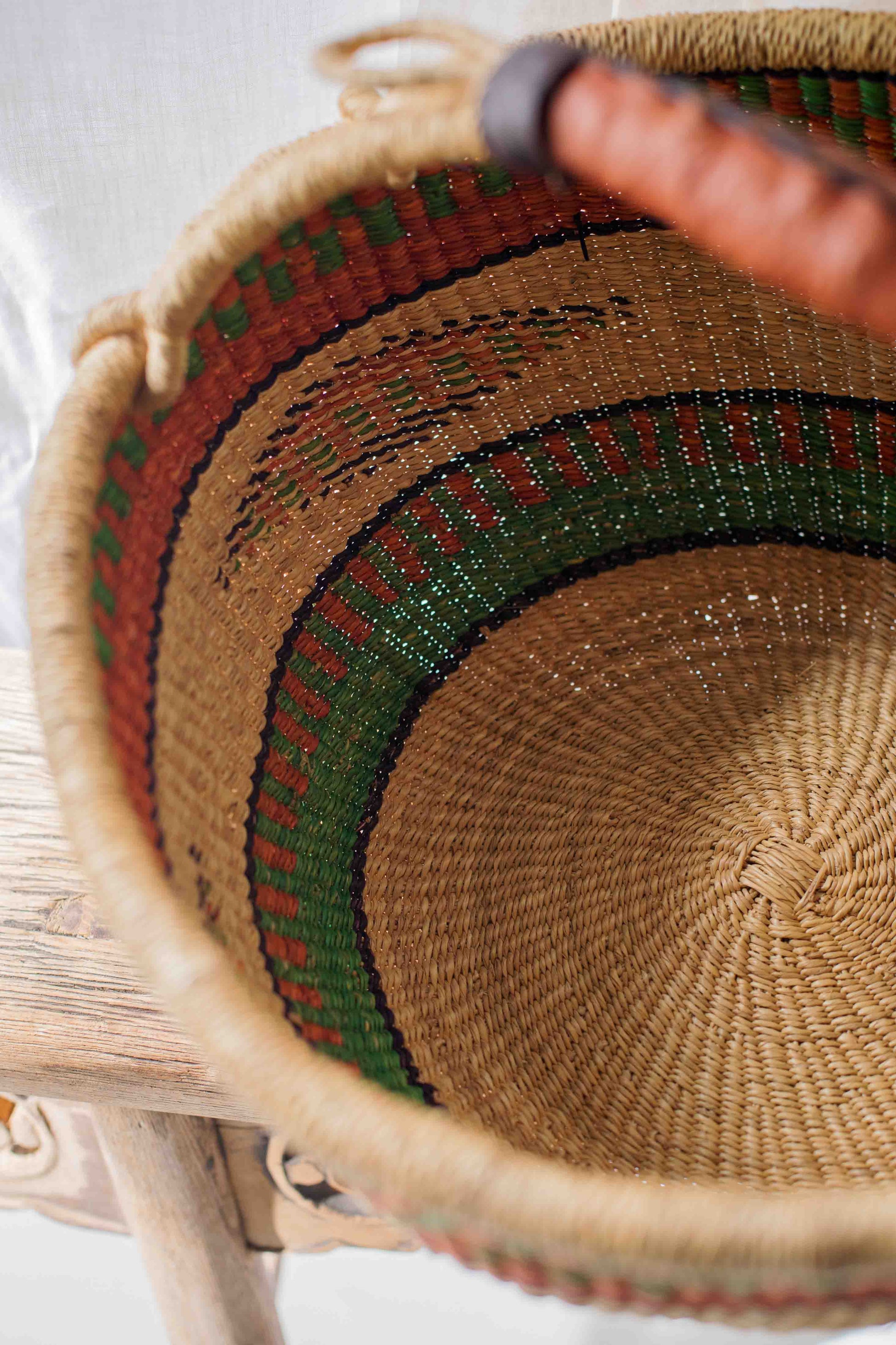 Close-up of a woven basket with a hand holding it