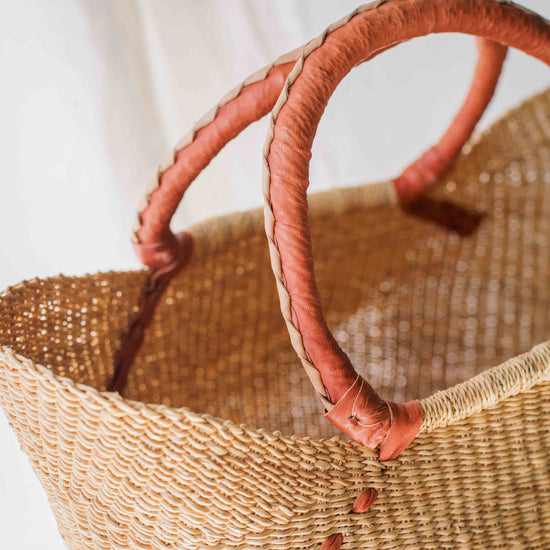 Woven basket with pink handles on a light background