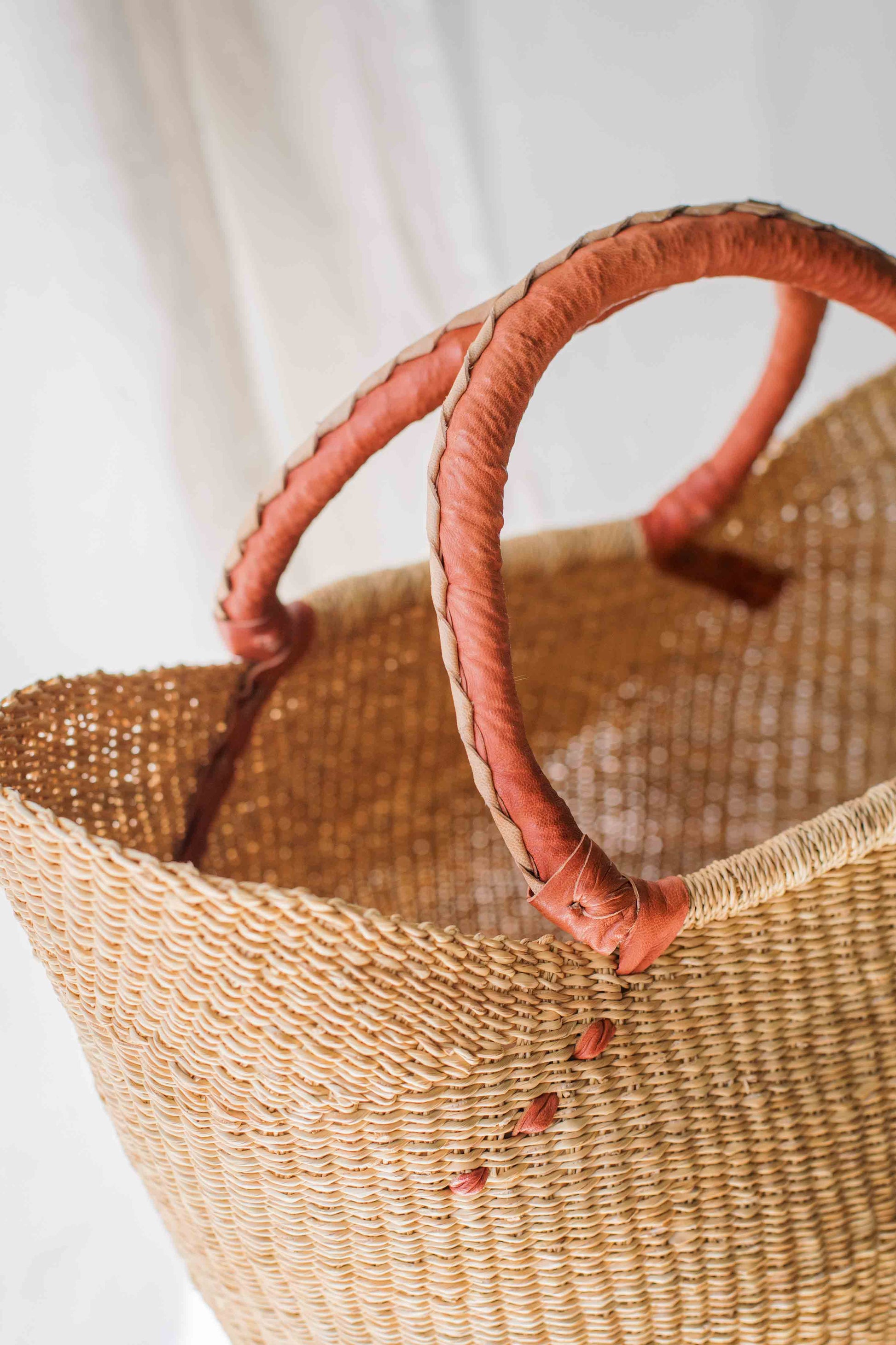 Woven basket with pink handles on a light background