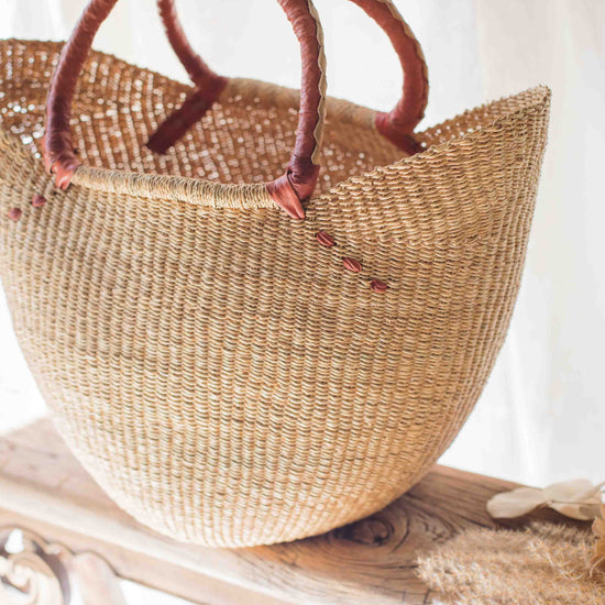 Woven straw bag with brown handles on a white surface