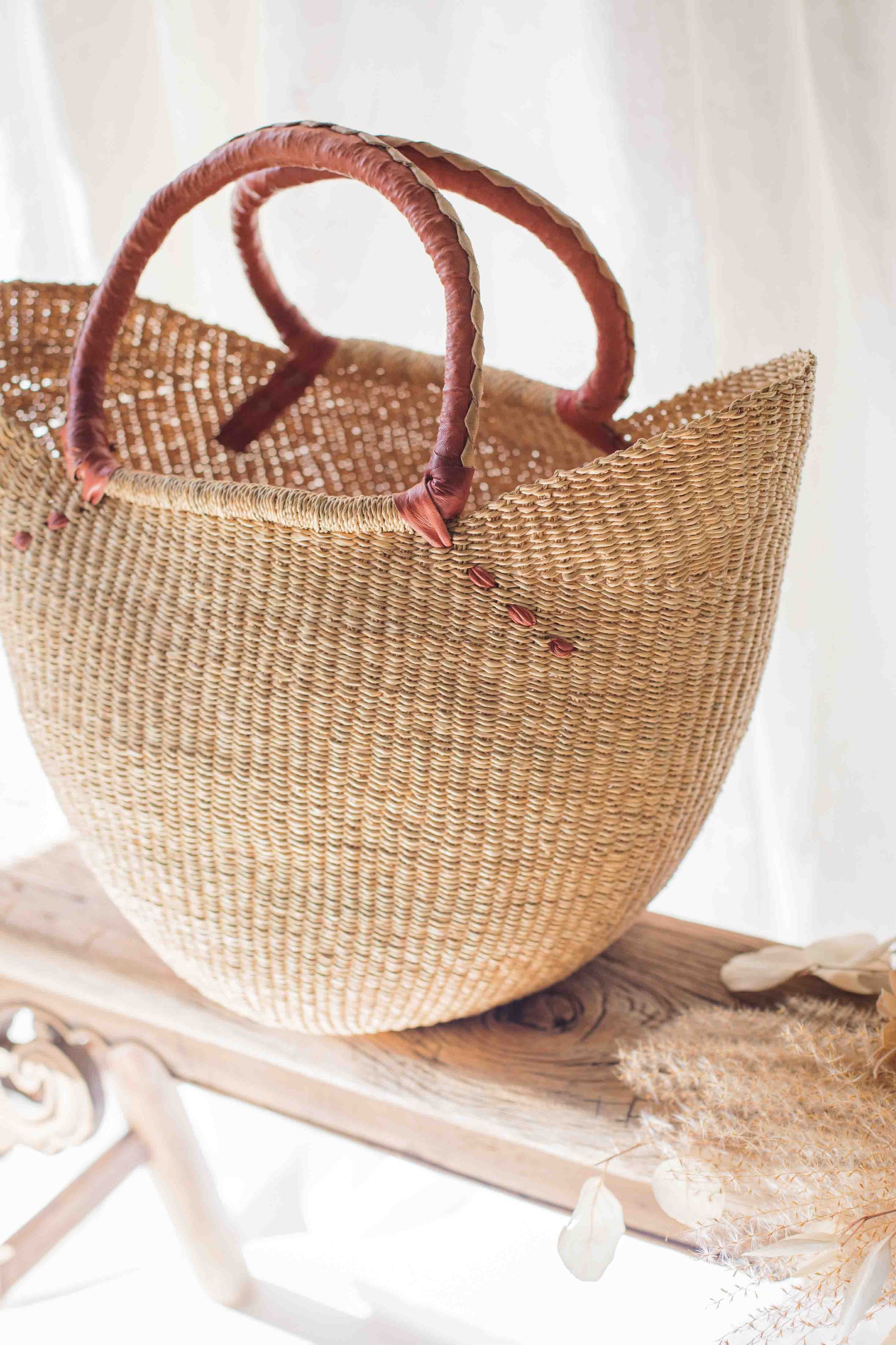 Woven straw bag with brown handles on a white surface